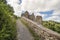 Ascent to a castle ruin on a hill on a path along a wall on a cloudy summer day