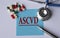 ASCVD - medical abbreviation on a blue sheet on the background of tablets, stethoscope and pen