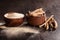 Ashwagandha root and powder in wooden cups on dark background.