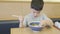 Asia cute boy eating hot Japanese noodles Udon or ramen with chopsticks on the table and sitting in the restaurant. He is very h