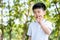 Asia cute boy or kid enjoys nose pick snot by using finger and standing in the public garden. Wearing a white t-shirt with copy