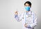 Asia man doctor wearing surgical mask and hand holding vaccine syringe and coronavirus testing form standing in gray wall