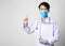 Asia man doctor wearing surgical mask and hand holding vaccine syringe and paper form standing in gray wall background.