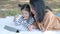 Asia mother lying on floor or ground with her daughter in the garden and play tablet device. Mom teach her how to use. Talking wit
