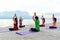 Asia people group making warrior pose on beach, fitness, sport, yoga and healthy lifestyle