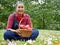 Asia senior woman holding red apple at public park.