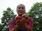 Asia senior woman holding red apple at public park.