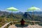 asia women traveler sit on the wooden terrace under of shadow umbrella look landscape view