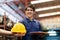 Asia young engineer standing in the automotive part warehouse at factory. Received safety helmet and smile. Worker holding