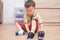 Asian 2 - 3 years old toddler boy sitting and concentrate on putting on his black shoes / sneakers