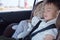 Asian 2 - 3 years toddler baby boy child sleeping in modern car seat. Child traveling safety on the road