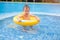 Asian 2 years old toddler boy child having fun playing with inflatable swim ring in wading pool for small children on hot summer d