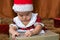 Asian adorable baby girl with Christmas red hat curiosity looking to present box, curiosity girl 6 month old try to remove wrappin