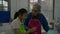 Asian adorable female teenager in apron tasting the food cooked by her senior grandfather in the kitchen.