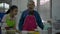 Asian adorable girl in apron enjoy eating mango with dipping sauce prepared with her elderly grandfather in the kitchen room.