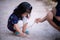 Asian adorable girl plays on dry ground with tree branch with his mother. Children play and learn with nature around them.