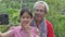 Asian adorable teen granddaughter posing and smiling while taking selfie photo from smartphone with her elderly grandfather.