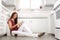 Asian american woman sitting on clean kitchen floor of her tiny home, enjoying leisure time with a book