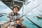 Asian angler smiles while holding a fishing rod on boat