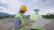 Asian architecture and engineer workers wear safety vest and safety helmet, protective face mask working together during pandemic