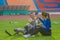 Asian athlete with prosthetics and trainer exchange a high-five on a grass lawn after a successful speed running practice at the