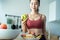 Asian attractive active woman pick up a green apple in kitchen at home. Beautiful sport girl in sportswear desire to chose fruit