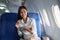 Asian attractive business woman passenger sitting on business class luxury plane while tablet computer while travel