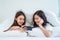 Asian attractive lesbian couple use mobile phone watch movie on bed. Beautiful sibling in pajamas lying down with blanket in