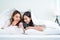 Asian attractive lesbian couple use mobile phone watch movie on bed. Beautiful sibling in pajamas lying down with blanket in