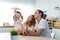 Asian attractive parents playing airplane toy with baby kid in kitchen. Happy family, young couple mother and father spend time on