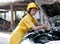 Asian automotive mechanic girl with yellow suit and helmet check the engine and system of the car during day time