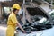 Asian automotive mechanic girl with yellow suit and helmet check the engine and system of the car during day time