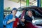 Asian automotive technician stand and show thumbs up with his customer who sit in car and smiling in workplace area after finish
