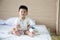 Asian baby boy smiling and wear patients suits sitting on bed in the room at child department in the hospital.