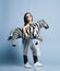 Asian baby girl kid in high fashion clothes and sunglasses going to event party with zebra metallic balloon under her arm on blue