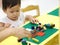 Asian baby playing puzzle toys with parent on yellow table indoor