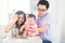 Asian baby putting coins into the glass bottle with help of pare