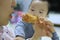 Asian baby seeing mother eating fried chicken with an envious eye