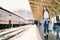 Asian backpack traveler woman holding generic local map and waving hand at train station platform summer holiday traveling concept