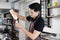 Asian barista young man pouring Sweetened condensed milk in glass  cup for make Latte coffee. Start up for cafe business.