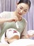 Asian beautician applying facial mask on face of young woman