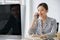 Asian beautiful female employee in black and white stripe shirt sit on chair smiling talk on phone while male worker on opposite