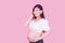 Asian beautiful pregnant woman stands relaxed and enjoys listening to music on headphones connected to the internet