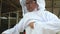 Asian beekeeper man wearing a white protective suit and glove to protect danger from bees sting before harvesting honeycomb in far