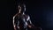 Asian bodybuilder demonstrates the inflated body, he is strong. Black background. Slow motion