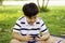 Asian boy with cute smile, with smartphones  in hand, standing in garden,  online learning concepts and e-learning with learning