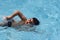 Asian boy front crawl swims in swimming pool