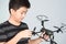 Asian boy holding and checking his hexacopter drone or quadrocopter toy in hand.