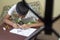 Asian boy learning and practicing to draw 3D shapes on drawing notebook on brown desk at home