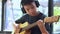 Asian boy learning to play the guitar in virtual meeting for play music online together with friend or teacher in video conference